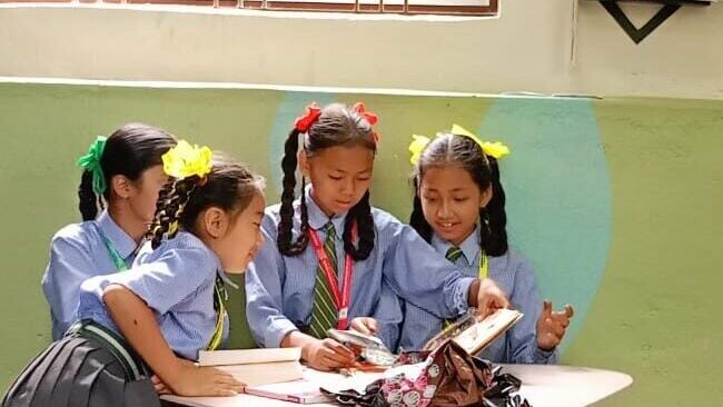 Vier Mädchen machen zusammen Hausaufgaben in der Bibliothek
