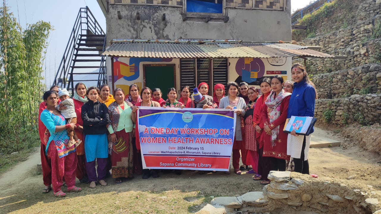 Gruppenbild: Frauen vor der Bibliothek, sie halten einen Banner zum "Women Health Awareness Workshop"