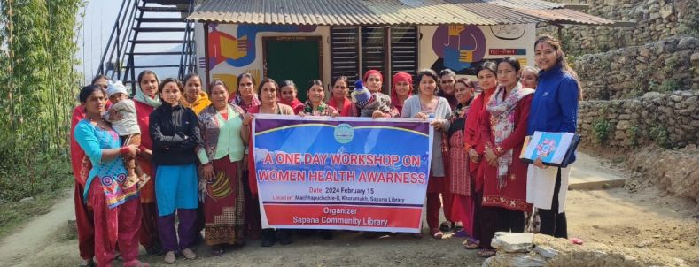 Gruppenbild: Frauen vor der Bibliothek, sie halten einen Banner zum "Women Health Awareness Workshop"